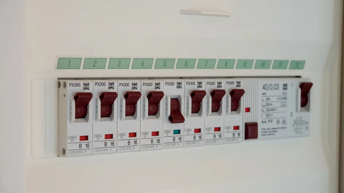 Quadro elétrico branco com disjuntores de chaves vermelhas na parede