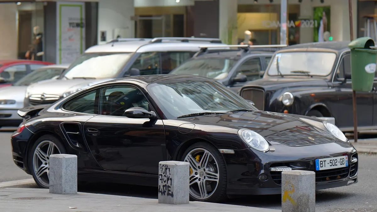 Carro esportivo preto estacionado na rua entre balizas de concreto
