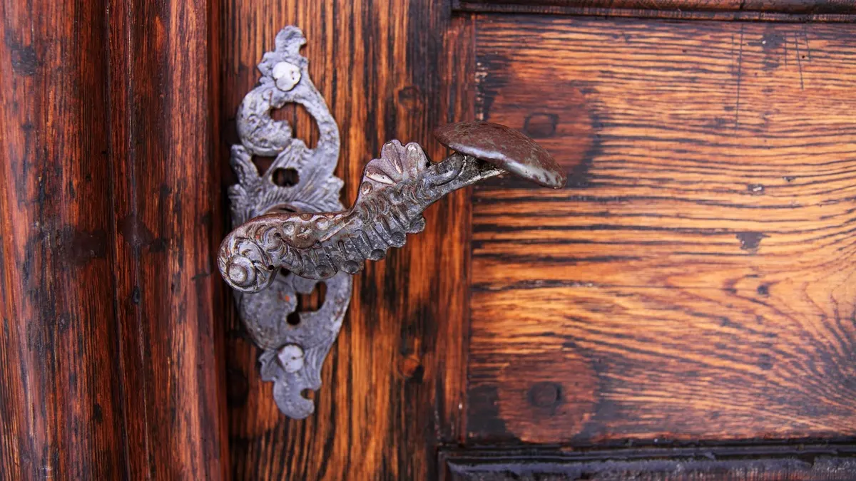 Maçaneta de metal ornamentada em porta de madeira escura